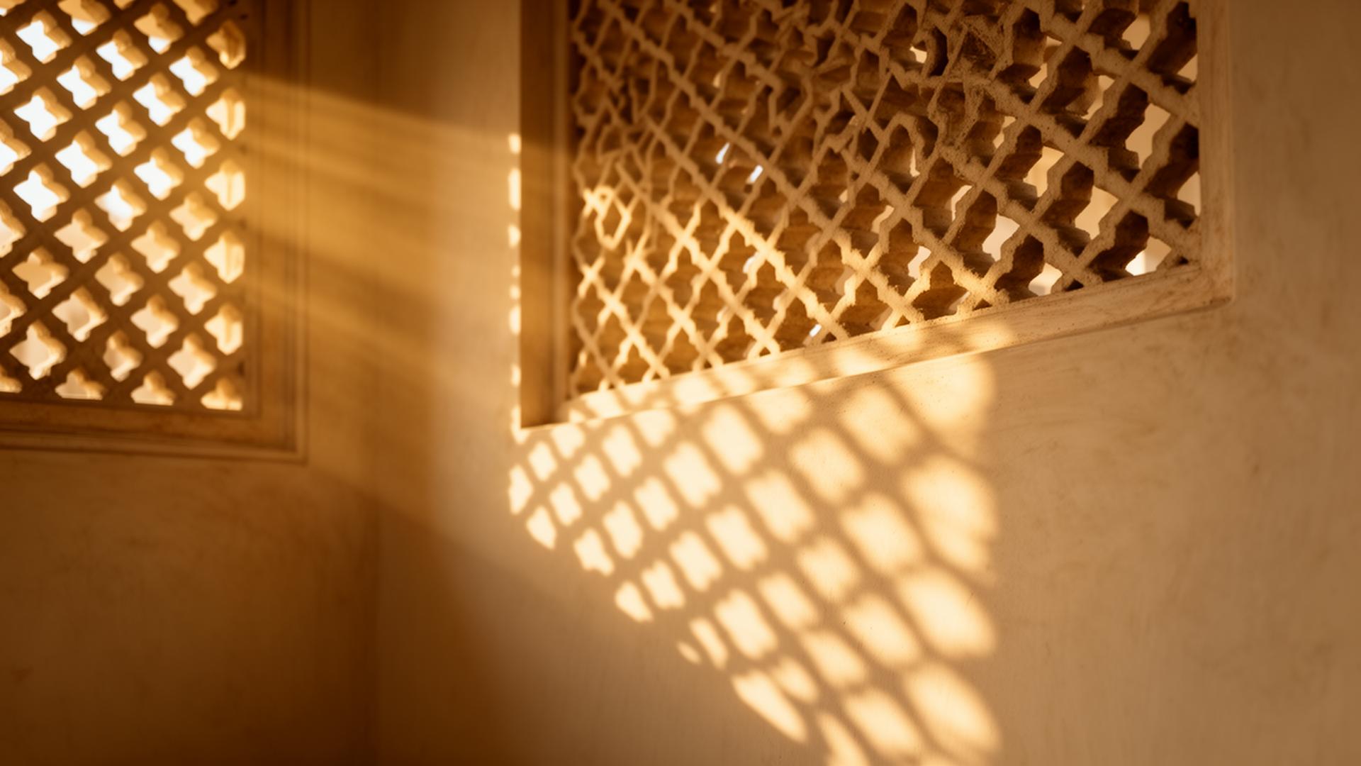 Light streaming through a carved mashrabiya screen onto a cream wall